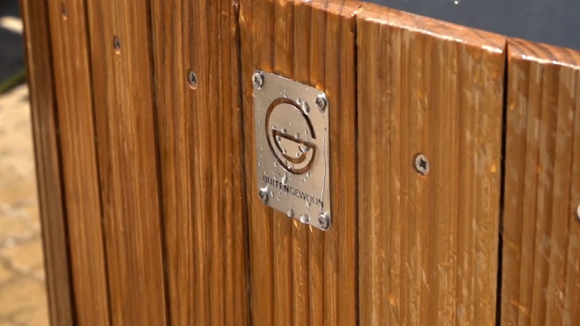 The buitengewoon logo on the wooden cladding with water dripping off it