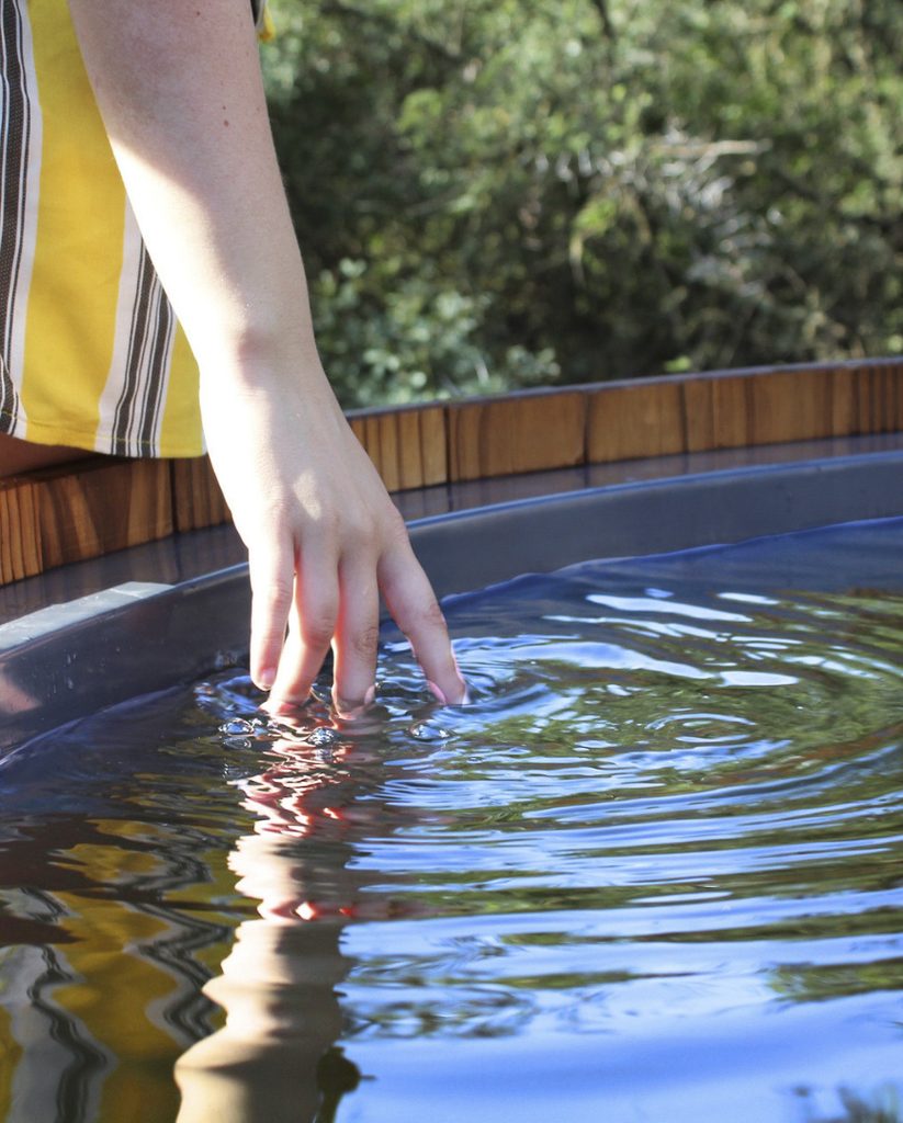 Hand trailing through warm water in an outdoor hot tub