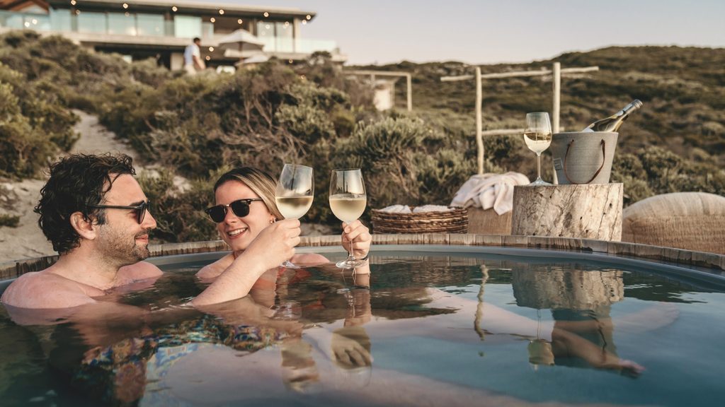 Couple relaxing with wine in a wood-fired hot tub outdoors