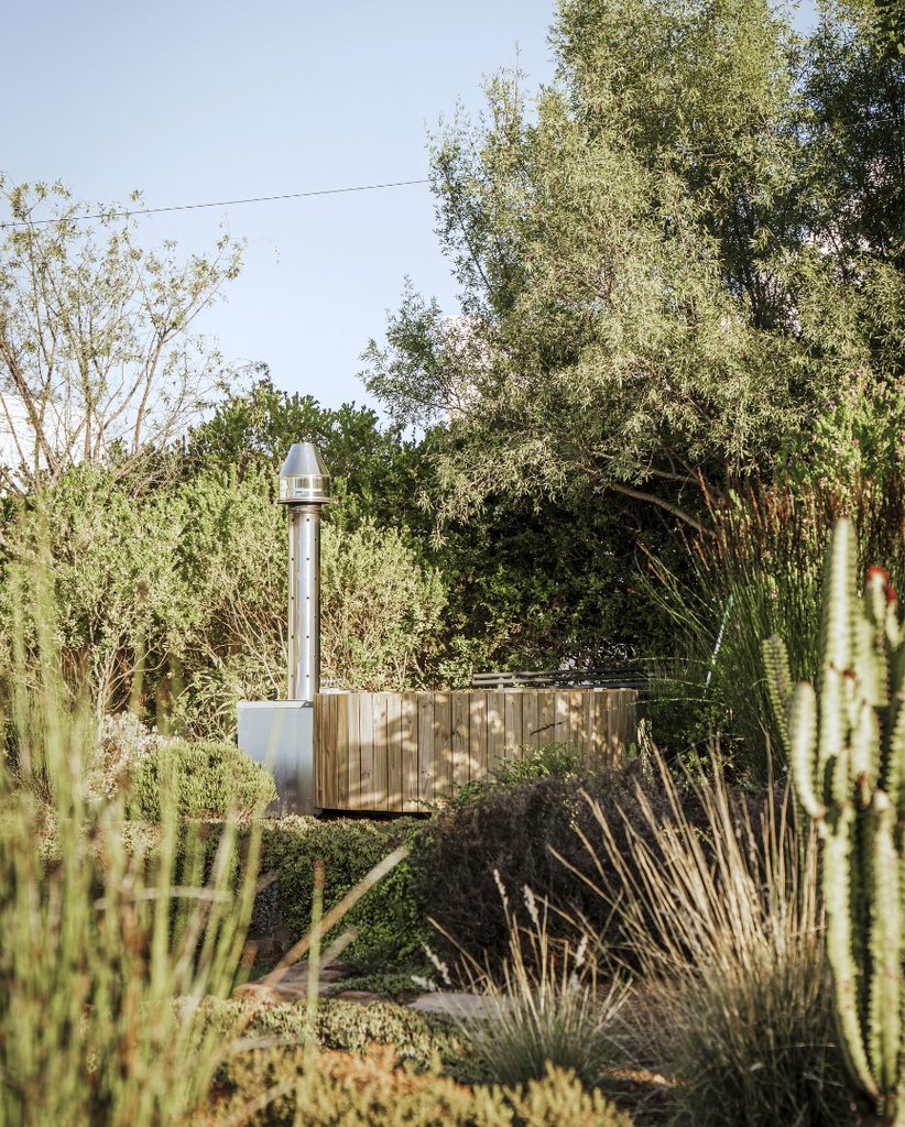 Wood-fired hot tub nestled amongst planting in a lush garden