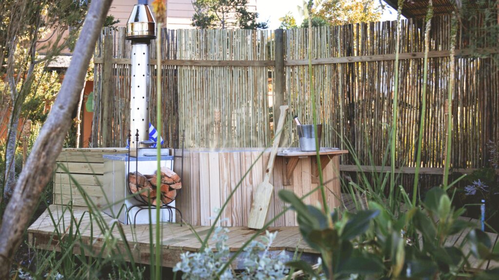 Wood-fired hot tub nestled with greenery on a deck in a back yard
