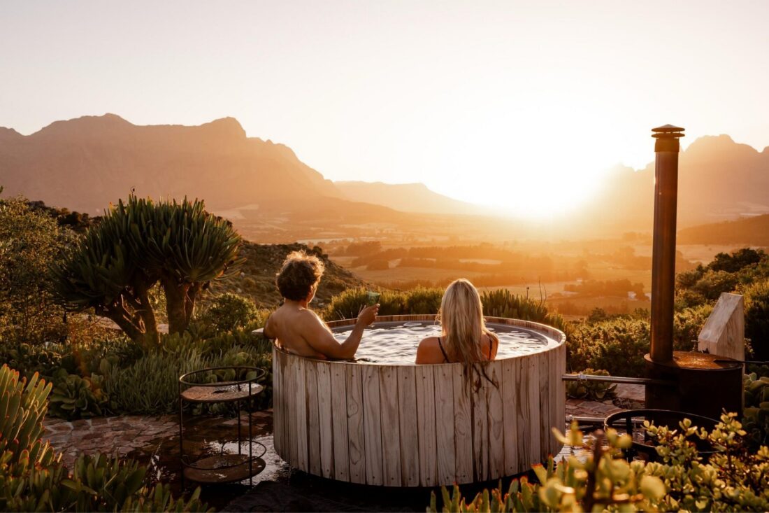 Couple relaxing in a Buitengewoon wood-fired hot tub overlooking the mountains near Franschhoek